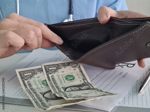 Poor doctor showing empty wallet with one dollar