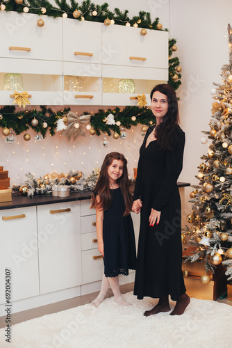 daughter and mother in a home Christmas settingchristmas tree, happy, merry, blonde, house, mother, alternative, concept, baby, setting, holidays, new year, eco friendly, forest, handcraft, fairy ligh photo