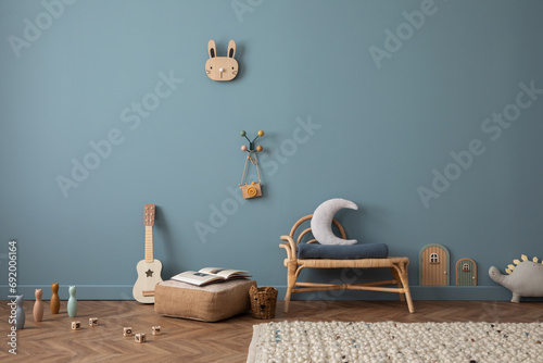 Stylish kid room with copy space, rattan bench, pouf, toys, teddy, decoration and personal accessories. Home decor. photo