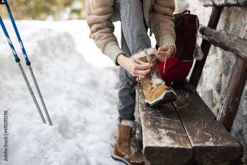 Картината върху платно Woman Ties Her Snowshoes While Getting Ready For Recreational Hike Outdoors on W
