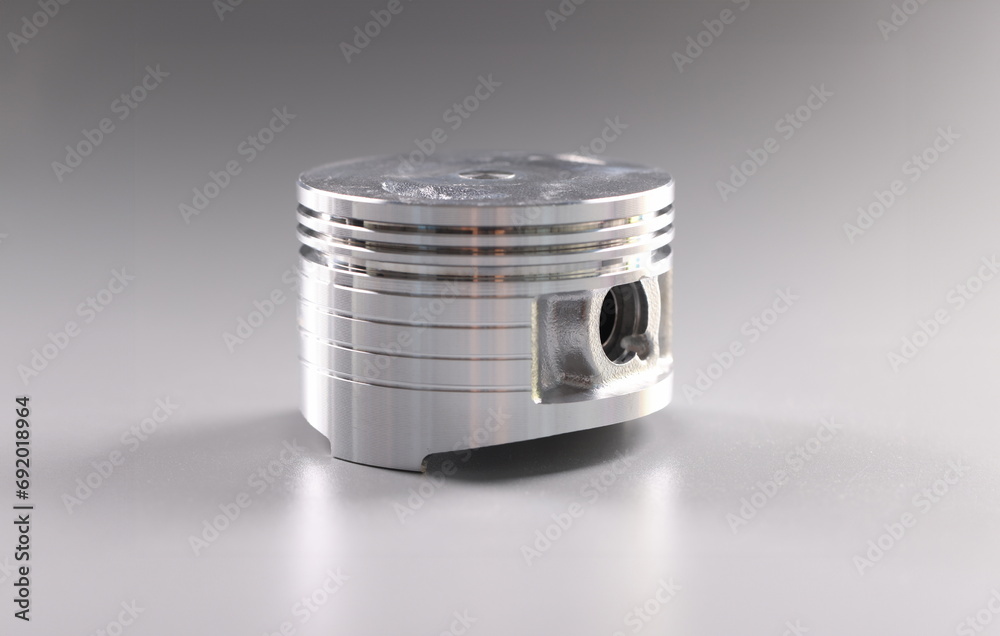 Close-up of metal new part for internal combustion engine placed in grey background. Piston detail for automobile vehicle. Transport, component concept Close-up of metal new part for internal combustion engine placed in grey background. Piston detail for automobile vehicle. Transport, component concept