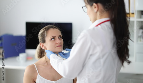 Doctor examining patients submandibular lymph nodes in clinic. Patient examination concept photo