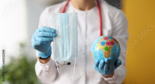 Doctor holding protective mask and globe closeup. Global global coronavirus pandemic concept photo