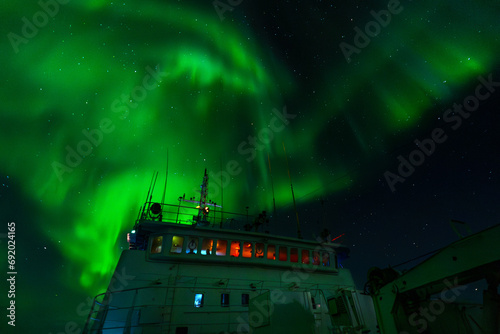 Green northern light, aurora borealis above big boat at night