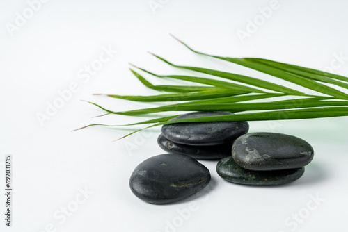 Black spa pebbles with leaves isolated on white background