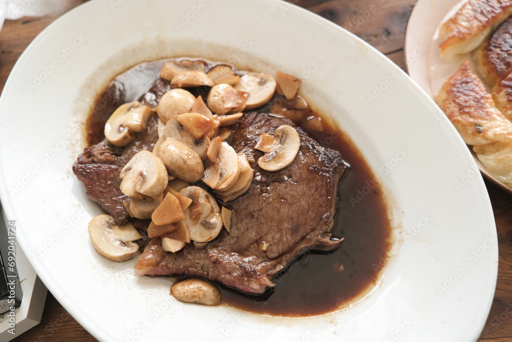 Beef steak with mushrooms on a white plate Beef steak with mushrooms on a white plate