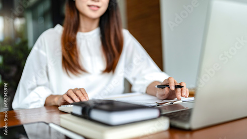 Writer woman calculate and check financial business document with calculator while working in cafe