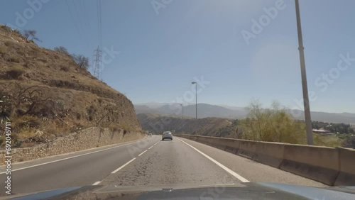 First person view, FPV, from dashcam of car driving from the Alhambra towards Granada in Andalusia, Sierra Nevada Mountains, Spain, Europe. Road trip video in POV, with bright, sunny, clear blue sky photo