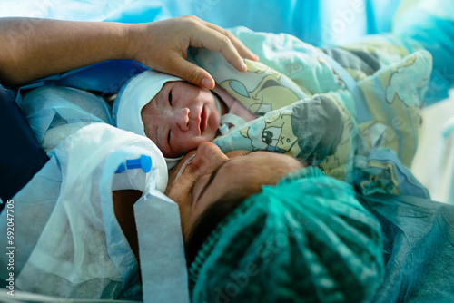Newborn baby with mother in hospital, seconds after birth. Infant in maternity hospital photo