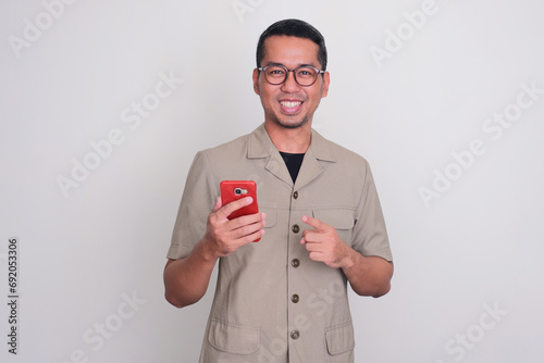 Indonesia government worker smiling while pointing to mobile phone that he hold photo