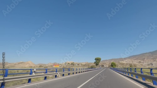 First person view, FPV, from dashcam of car driving in the Tabernas desert in Almeria, Andalusia, Spain. Arid setting of spaghetti western films. Road trip video in POV, with bright, sunny, clear sky photo