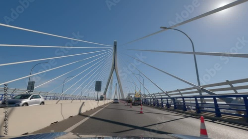 First person view, FPV, from dashcam of car driving across the Constitution of 1812 Bridge, La Pepa, in Cádiz, Andalusia, Spain, Europe. Road trip video in POV, with bright, sunny, clear blue sky photo