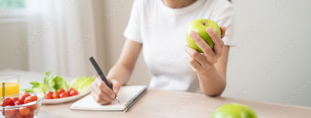Wellbeing of health with good food control concept. Woman writing the meal note and plan to eat during diet program to loss weight goal for balance nutrition and calories. - obrazy, fototapety, plakaty 