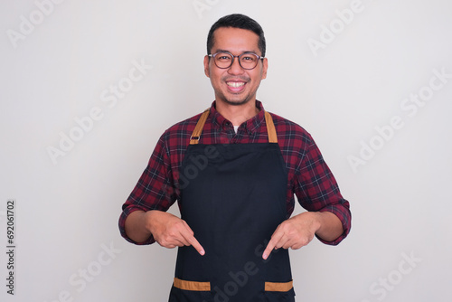 A man wearing apron smiling happy with both hands pointing down photo