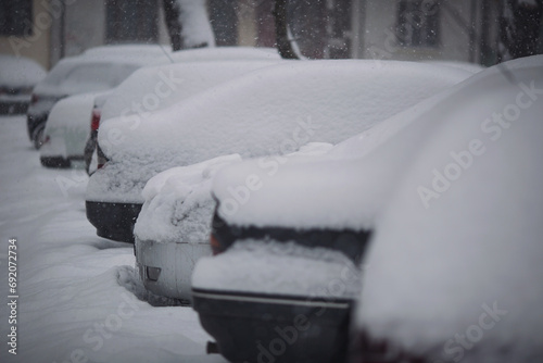 Parking lot with cars covered in fresh snow. Concept: winter weather and car owner confrontation. Snowfall in the city, falling snowflakes. increased precipitation and snow levels. photo