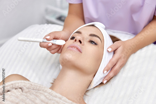 female hand touching the patient's face with a brush. beautician applies the mask to female face. facial skin care.
