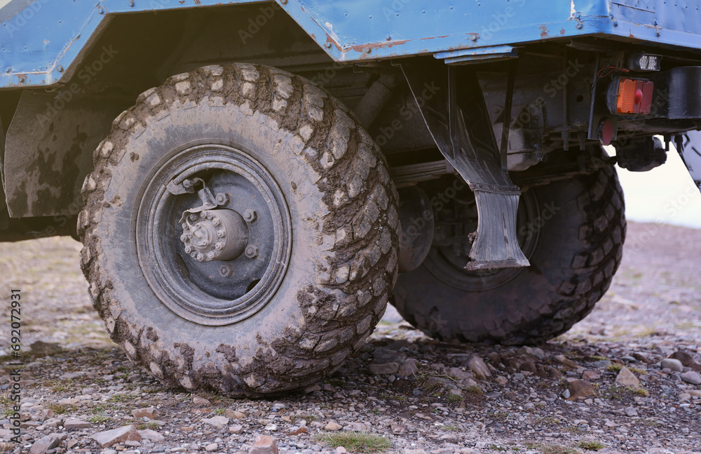 Wheel closeup in a countryside landscape with a mud road. Off-road 4x4 suv automobile with ditry body after drive in muddy road area Wheel closeup in a countryside landscape with a mud road. Off-road 4x4 suv automobile with ditry body after drive in muddy road area