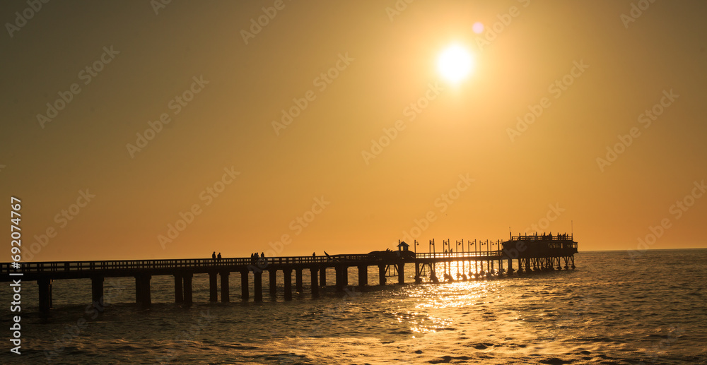 Swakopmund Pier with a beautiful Orange Sunset and silhouette of people on the pier