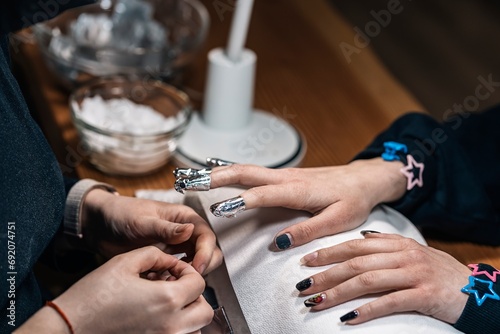 Crop faceless women with nail artist and removal gel nail polish using foil in salon photo