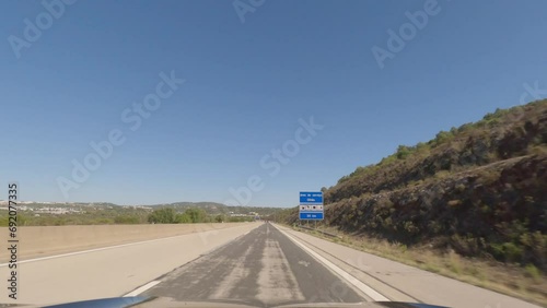 First person view, FPV, from dashcam of car driving along the Algarve Coast in Portugal, driving on the highway towards Faro. Road trip video in POV, with blue sky	 photo