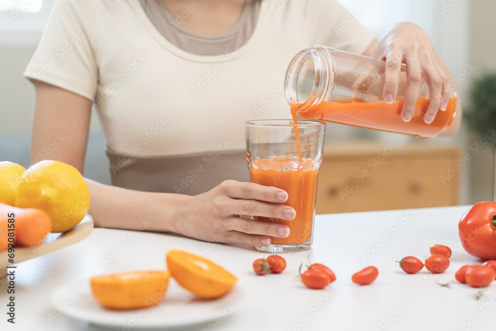Detox juice concept, hand of woman holding bottle making carrot, vegetable smoothie pouring in glass for diet at home, female drinking healthy meal food for weight loss. Lifestyle vegan nutrition. Detox juice concept, hand of woman holding bottle making carrot, vegetable smoothie pouring in glass for diet at home, female drinking healthy meal food for weight loss. Lifestyle vegan nutrition.
