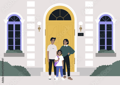 A full length family portrait, a Caucasian couple and their child at the entrance door on a first day of school
