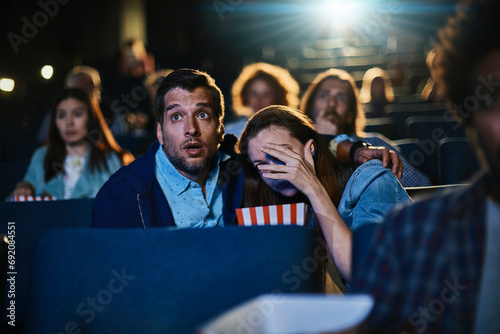 Scared young couple watching scary movie at theater photo