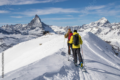 Back view of unrecognizable men with ski on snow-capped mountain on cloudy day in Zermatt photo