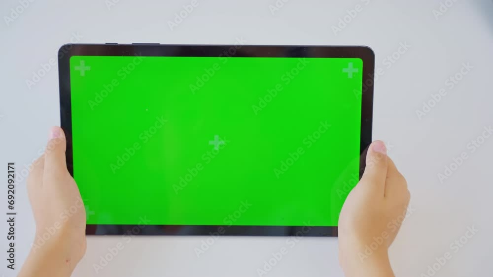 Close up kids hands holding, tapping on a tablet with green screen. Mock up Close up kids hands holding, tapping on a tablet with green screen. Mock up