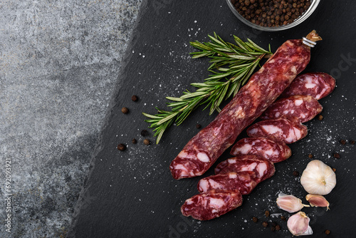 Smoked sausage salami and spices on black background. photo