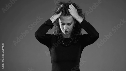Dramatic desperate scene of woman pulling hair in black and white. Person feeling dread and preoccupation photo