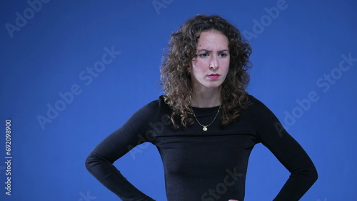 Photography Shocked woman reacting with perplexity on blue background with hands on hip, sur