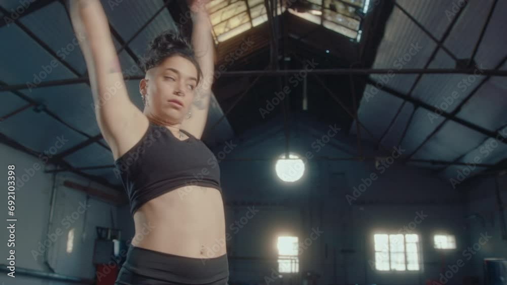 Young sportswoman rotating her torso from side to side and swinging arms during warm up routine in gym. Zoom shot Young sportswoman rotating her torso from side to side and swinging arms during warm up routine in gym. Zoom shot