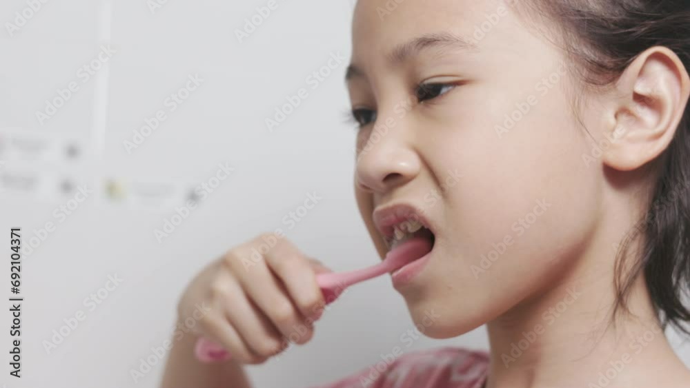 Close up face and mouth of Adorable little Asian girl enjoys her morning routine in relaxed expression for brushing her teeth in clean and bright bathroom for healthy dental care of kid and child. Close up face and mouth of Adorable little Asian girl enjoys her morning routine in relaxed expression for brushing her teeth in clean and bright bathroom for healthy dental care of kid and child.
