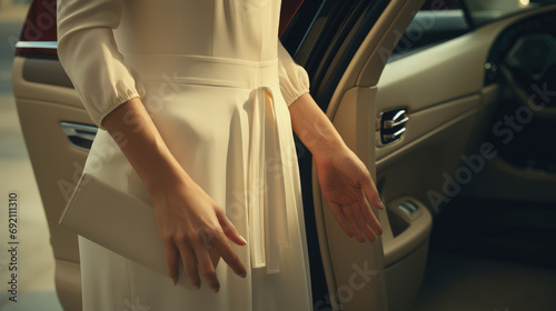 Close-up cropped photo of elegant business woman getting into car, hand opening car door. A new car, a carsharing service with business class cars. photo