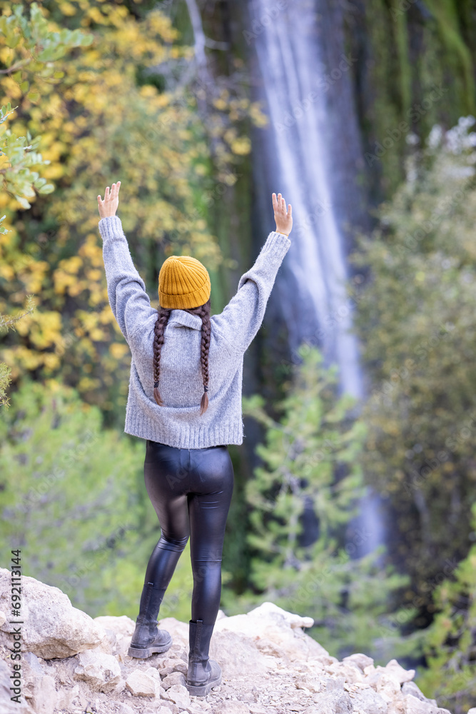 Young girl with arms up feels excited outdoors in autumn