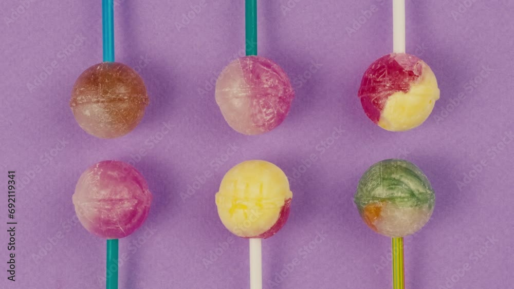 Vidéo Stock Sweet lollipops on color purple background zoom frame ...