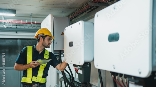 Technician Engineering setting inverter solar panel in electrical room. Service engineer installing solar cell on the roof of factory. Clean and Renewable energy concept. photo