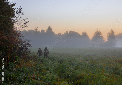 Two men with guns go in search of hunting object at sunrise. photo