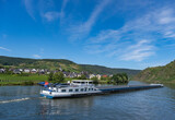 Frachtschiff fährt auf dem Fluss Mosel zwischen Beilstein und Cochem entlang der typischen Landschaft des Moseltales mit Weinbergen und Dorfidylle im Sommer ..