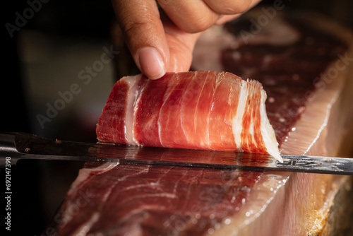 Jamón Ibérico de bellota típico de España. Lonchas de Jamon iberico de bellota para degustación cortadas a cuchillo de jamon iberico español. Preparación de un Jamón Ibérico para comer . photo