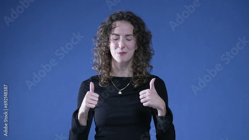 Proud woman pointing to self giving thumbs up recognizing her own success photo