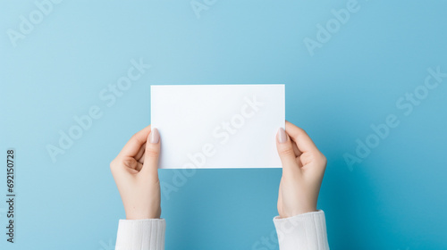 Bright and inviting portrayal of woman's hands presenting folded blank paper sheet or booklet, against pastel blue background, Focus on crispness of paper and clean, AI Generated