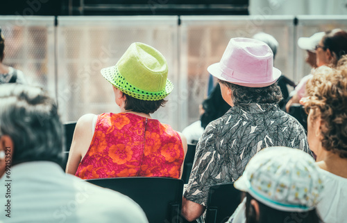 Rear view with a senior women wearing an elegant hat in the center of Bucharest. Audience at a free performance on Victoriei Street (Calea Victoriei) in Bucharest, Romania. photo