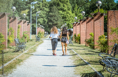 Two girls holding hands and walking on the gravel alley in King Mihai I park in Bucharest, Romania. photo