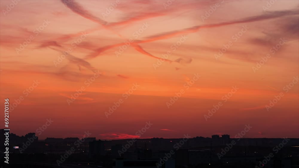 Time lapse of night city. Silhouette of downtown buildings and illuminated highways appears on the bright orange and red sunset sky background. A lot of airplanes draw colorful traces on the sky Time lapse of night city. Silhouette of downtown buildings and illuminated highways appears on the bright orange and red sunset sky background. A lot of airplanes draw colorful traces on the sky