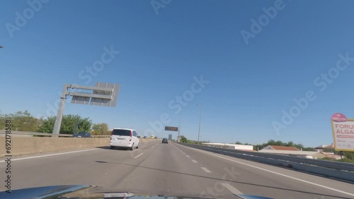 First person view, FPV, from dashcam of car driving along the Algarve Coast in Portugal, driving on the highway towards Faro. Road trip video in POV, with blue sky	 photo