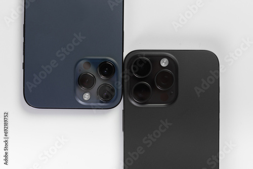 two smartphone cameras on a white background, , Iphone 15 pro max Black Titanium, iphone 12 pro max