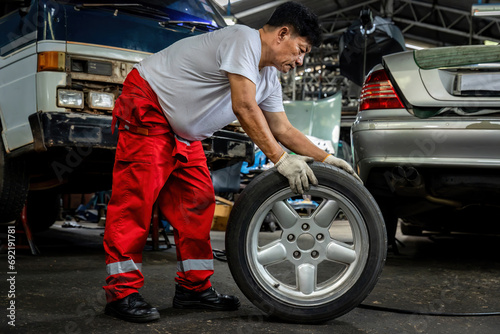 Mechanician changing car wheel in auto repair shop. changing wheels/tires. Concept of car care service and maintenance or fix the car © kanpisut