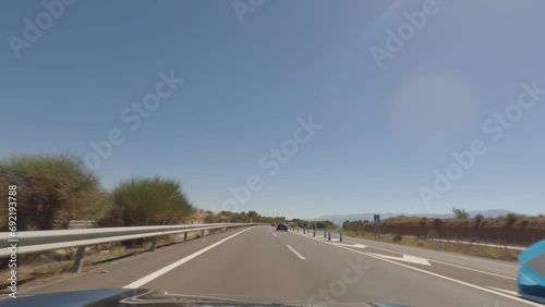 First person view, FPV, from dashcam of car driving fast on the highway towards the Tabernas desert in Almeria, Andalusia, Spain, Europe. Road trip video in POV, with bright, sunny, clear sky photo